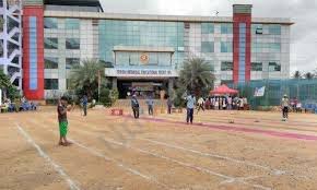 A vibrant view of Triveni Public School's main building, featuring a modern glass façade, a neatly maintained sports ground, and students engaged in outdoor activities.