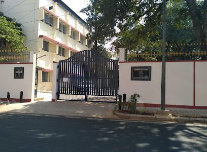 The front entrance of Tunbridge High School, featuring a gated compound with a white boundary wall, school signage, and a well-maintained road in front.